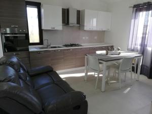 a kitchen with a table and a couch and a table and chairs at Casa Cristina in Costa Rei