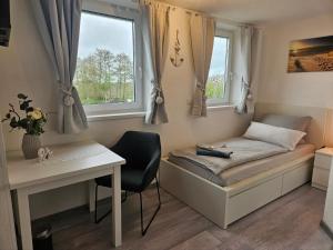 a small bedroom with a bed and a desk at Pension Hohaus in Neuharlingersiel
