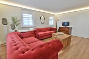 a living room with a red couch and a tv at Ferienwohnung Harmony "Residenz" in Leisnig