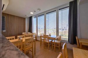 a restaurant with wooden tables and chairs and large windows at Old Town Guest Accommodation in Kranj