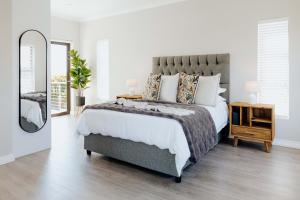 a bedroom with a large bed and a mirror at Salt & Feather in Yzerfontein +34 photos