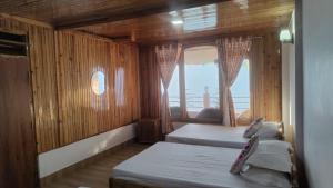 a bedroom with two beds and a large window at Dafey Homestay in Darjeeling