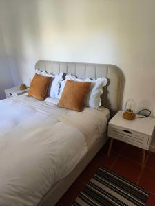 a bedroom with a large white bed with two pillows at Oficina do Avô in Villa Nogueira