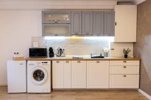 a kitchen with white cabinets and a washer and dryer at Studio Glen in Târgu-Mureş