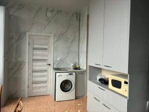a kitchen with a washing machine and a microwave at Pariss Library Hostel in Yerevan