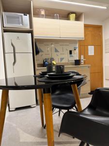 a kitchen with a table with black chairs and a refrigerator at 710 A Hotel Home Jade in Brasília