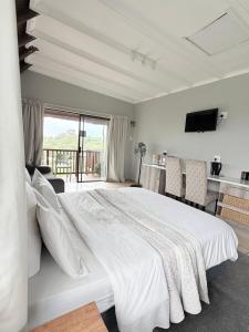 a white bedroom with a large bed and a balcony at The Hide on 37 Flamingo in East London