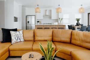 a living room with a brown couch and a kitchen at Salt & Feather in Yzerfontein