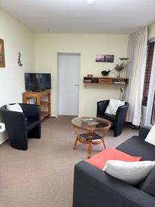 a living room with couches and a table and a tv at Ostseeferienwohnung - Bossert in Kronsgaard
