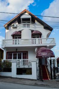 a white house with a porch and a balcony at Guest House Vivaldi in Niš