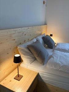 a bed with two pillows and a table with a lamp at Casa ecologica Ai Ronchi in Gallio +8 photos