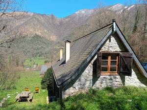 a small stone house with a window and a table at Bergerie Macha in Ustou