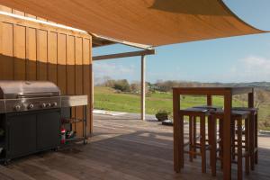 a patio with a grill and two bar stools at HavenRidge Alpaca Glamping Cabins in Kaiwaka