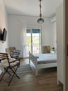 a white bedroom with a bed and a window at Ekati in Xylokastro +1 photo