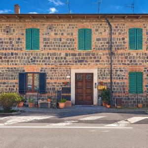 a brick building with green shutters and a wooden door at La casa di Armida in Radicofani