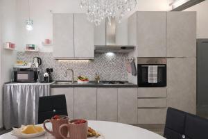 a kitchen with white cabinets and a table and a chandelier at La casa di Armida in Radicofani