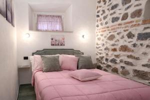 a bedroom with a pink bed with a stone wall at La casa di Armida in Radicofani