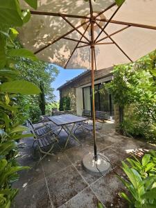 a picnic table with an umbrella on a patio at La Ribaude in Crestet