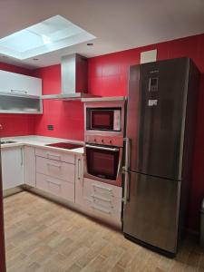 a kitchen with red walls and a stainless steel refrigerator at Southbay Alquiler in San Fernando