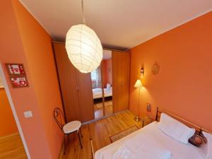 a bedroom with orange walls and a bed and a chandelier at Appartement Sandra im Bayerischen Wald mit Pool in Freyung +31 photos