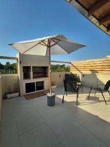 a patio with an umbrella and a table and chairs at ÁMBAR DEPARTAMENT boutique in Monte Grande