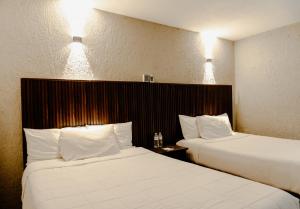 two beds in a hotel room with white sheets at Hotel La Antigua Express in San Cristóbal de Las Casas