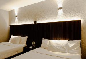 two beds in a hotel room with lights above them at Hotel La Antigua Express in San Cristóbal de Las Casas
