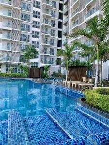 a large swimming pool with palm trees and buildings at The SB Residences Luxury Executive Studio in Iloilo City