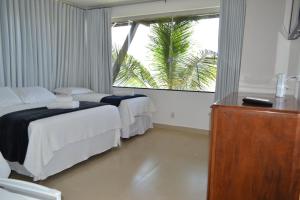 a hotel room with two beds and a window at Pousada Suítes do Lago in Capitólio +269 photos