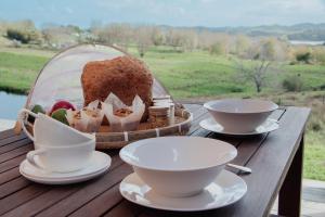 a table with two cups and a basket of food at HavenRidge Alpaca Glamping Cabins in Kaiwaka
