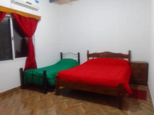 two beds with red and green sheets in a room at Hospedaje Ayla in Tinogasta +2 photos