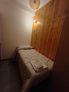 a small bedroom with a bed with a wooden wall at Eva House 2 in Fanano
