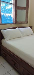 a bed with two pillows and a window at Perfect Backpacker Spot in Shimoni