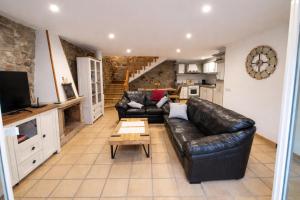a living room with a black leather couch and a table at Casa O Castriño in Cambados +39 photos