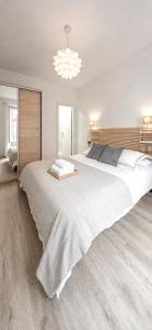 a large white bed in a bedroom with a chandelier at 22CaLQuEROL Boutique centro suite lux in Puigcerdà +5 photos