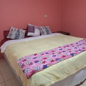 a large bed with a floral blanket on it at Abril hospedaje in Juayúa