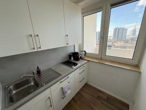 a kitchen with a sink and a large window at Cloud 12 - Penthouse in der Innenstadt mit Blick über die gesamte Skyline von Bremerhaven in Bremerhaven