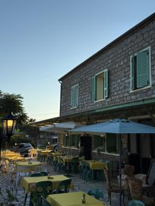 an outdoor patio with tables and umbrellas in front of a building at La Châtaigneraie in Evisa
