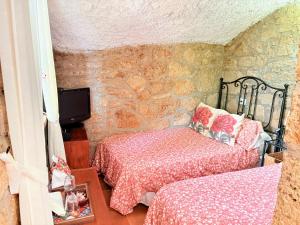 a bedroom with two beds and a stone wall at Finca Las Polinarias Casa Cueva en Fasnia in Santa Cruz de Tenerife