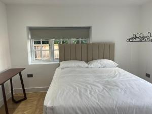 a bedroom with a large white bed with a window at Luxury 4BR Bungalow in Hackbridge