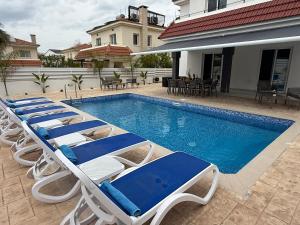 a row of lounge chairs next to a swimming pool at Villa Artemis - 150m from Kapparis Beach in Paralimni
