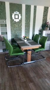 a table and four green chairs in a room at Ferienwohnung Heidebergblick in Lawalde