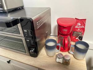 a counter top with a microwave and cups on it at Shiraz Suite in Calgary