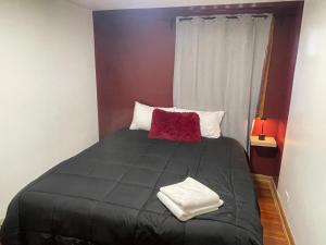 a bedroom with a black bed with a red pillow at Shiraz Suite in Calgary