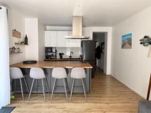a kitchen with a large wooden table and white stools at 3 pièces avec terrasse arborée in Arcachon