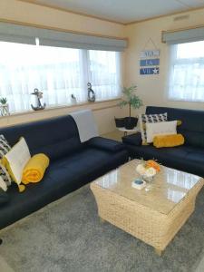 a living room with a blue couch and a coffee table at Holiday Sea Caravan in Withernsea