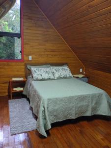 a bedroom with a bed with a wooden wall at Cabana mandaçaia in Timbe do Sul