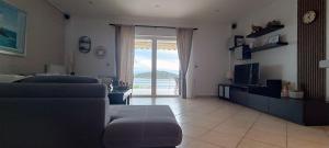 a living room with a couch and a tv at Sea & Mountain View Apartment in Chalkida