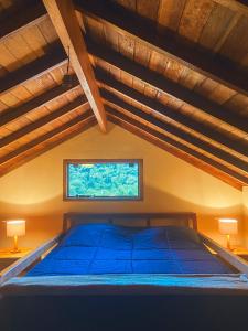 a bedroom with a blue bed with a window at La Maison De Bonneval in São Bento do Sapucaí