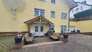 a yellow house with two benches in front of it at Appartements & Ferienwohnungen Wolf in Usingen